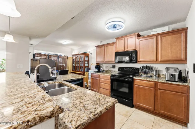 a kitchen with granite countertop a stove sink and refrigerator