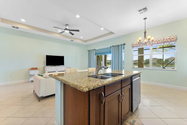 a dining hall with stainless steel appliances granite countertop a sink dishwasher and a flat screen tv