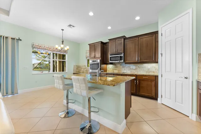 a kitchen with kitchen island granite countertop a stove a sink a counter space and cabinets