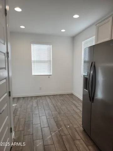 a view of a refrigerator in kitchen and an empty room