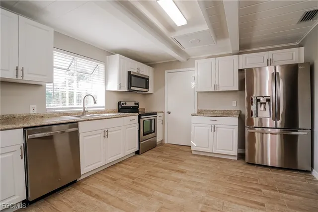a kitchen with a refrigerator wooden floor a sink and a window