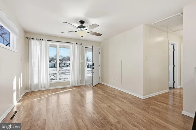 an empty room with wooden floor fan and windows