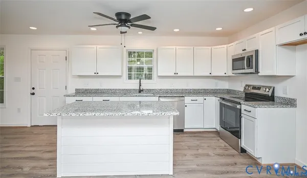a kitchen with stainless steel appliances granite countertop a stove a sink and white cabinets