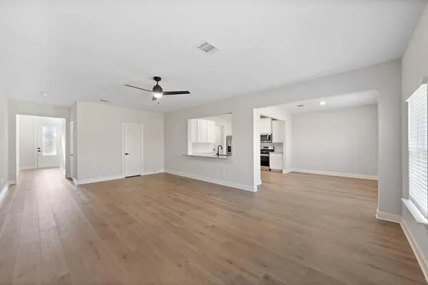 a view of an empty room with wooden floor and a window