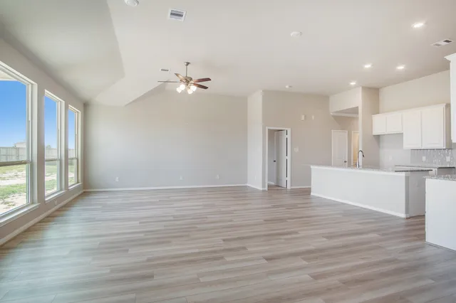 a view of an empty room with a kitchen and wooden floor