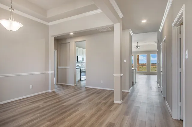 a view of a hallway with wooden floor and a bathroom