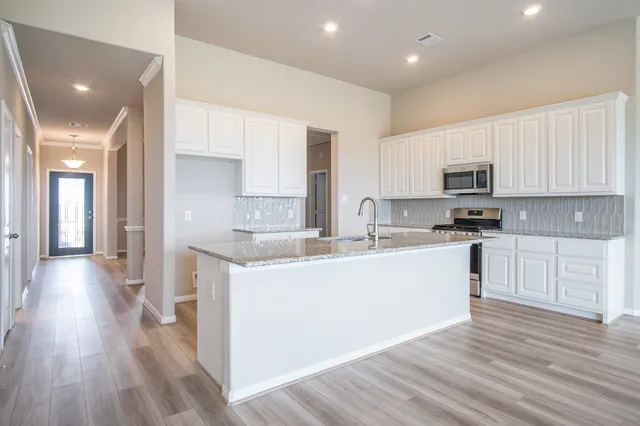 a large kitchen with cabinets wooden floor and stainless steel appliances