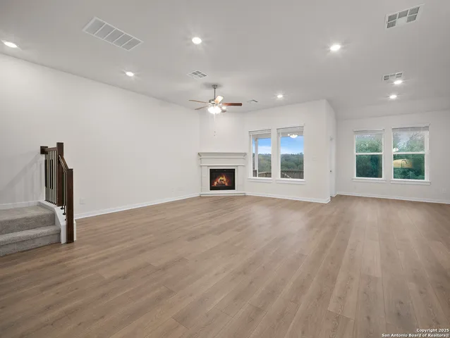 an empty room with wooden floor fireplace and windows