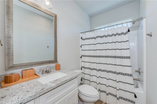 a bathroom with a granite countertop sink toilet and shower