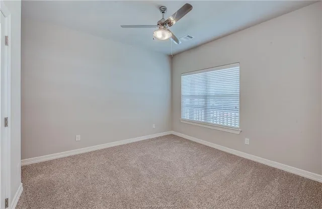 an empty room with a window and a fan
