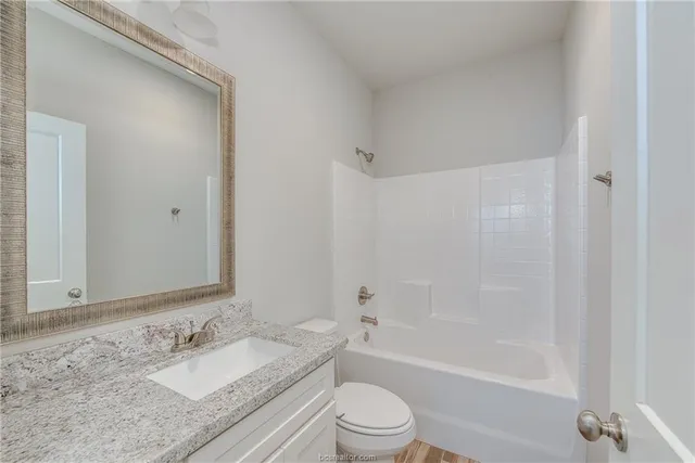 a bathroom with a granite countertop sink toilet and shower