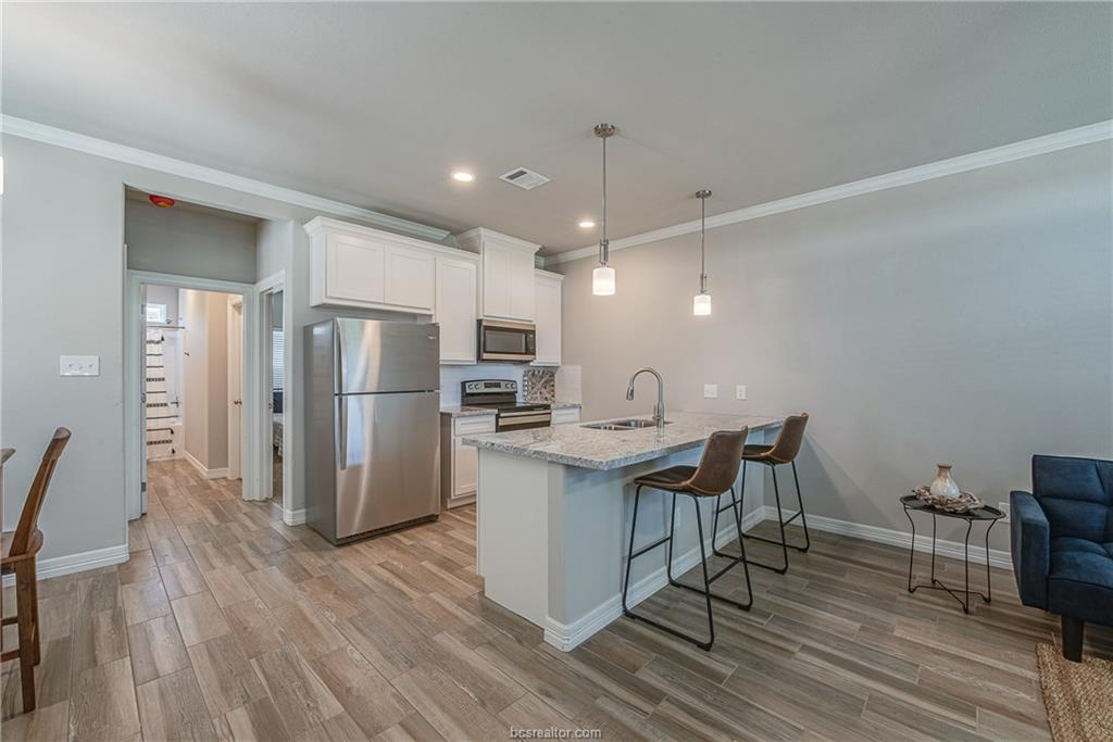 404 Poplar Street, Unit A College Station, TX 77840 - Photo 7 of 20 a kitchen with stainless steel appliances a refrigerator a stove a sink dishwasher with a dining table and chairs with wooden floor