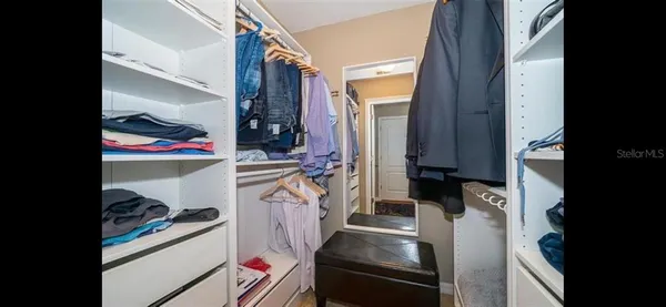 a view of walk in closet with clothes and shoes