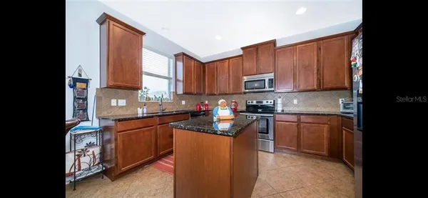 a kitchen with stainless steel appliances granite countertop a stove top oven a sink dishwasher and a microwave oven on the blue kitchen countertops