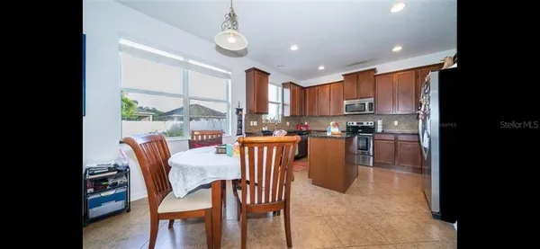 a kitchen with stainless steel appliances granite countertop a stove a refrigerator a kitchen island with a dining table and chairs