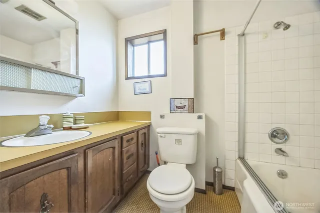 a bathroom with a granite countertop toilet a sink a mirror and a bathtub