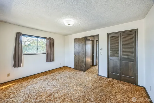 a view of an empty room with window and closet area