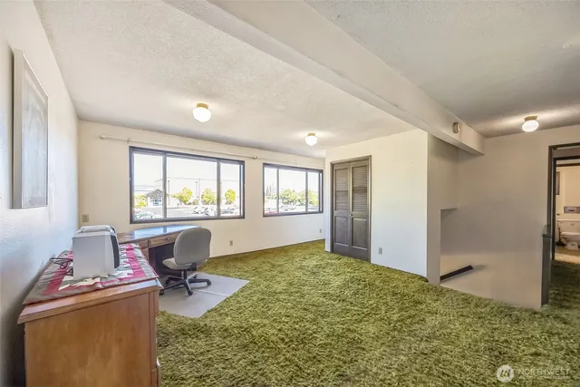a view of a workspace with furniture and a window