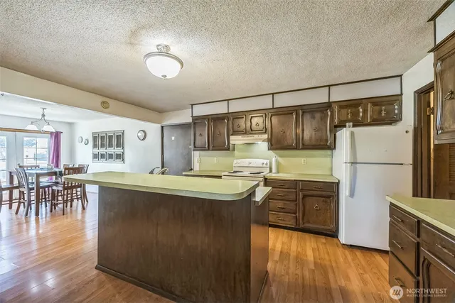 a kitchen with stainless steel appliances granite countertop a refrigerator a stove and a wooden floors