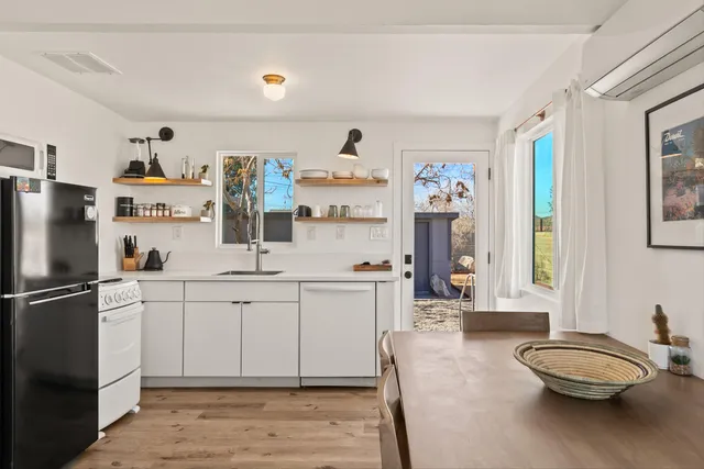 a kitchen with stainless steel appliances a sink a stove a refrigerator cabinets and a dining table