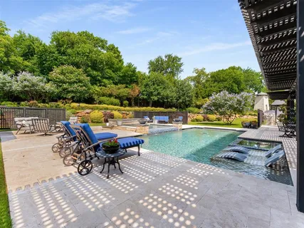 a view of a swimming pool and lounge chairs in back yard of the house