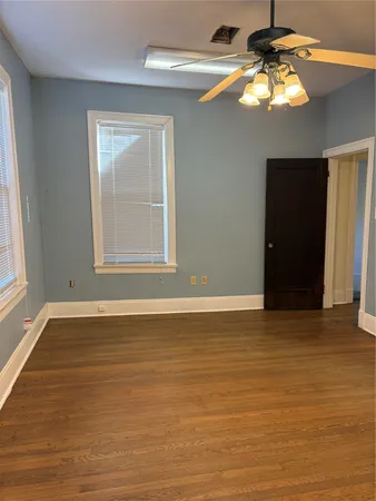 a view of an empty room with window and wooden floor