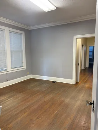 a view of an empty room with wooden floor and closet