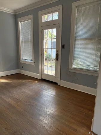 an empty room with wooden floor and windows