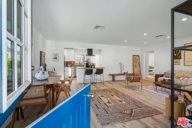 a living room with furniture kitchen view and a large window