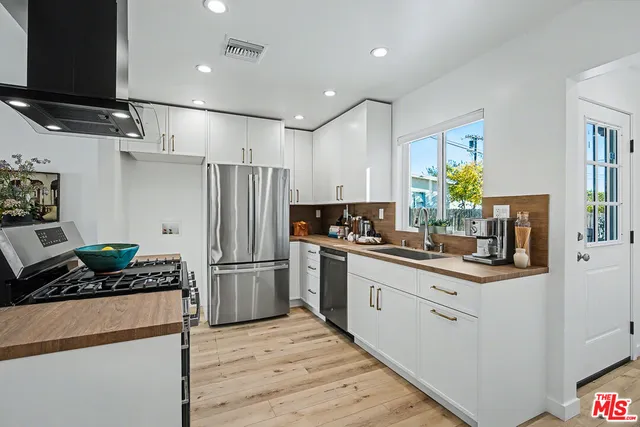 a kitchen with stainless steel appliances kitchen island granite countertop a refrigerator stove and sink