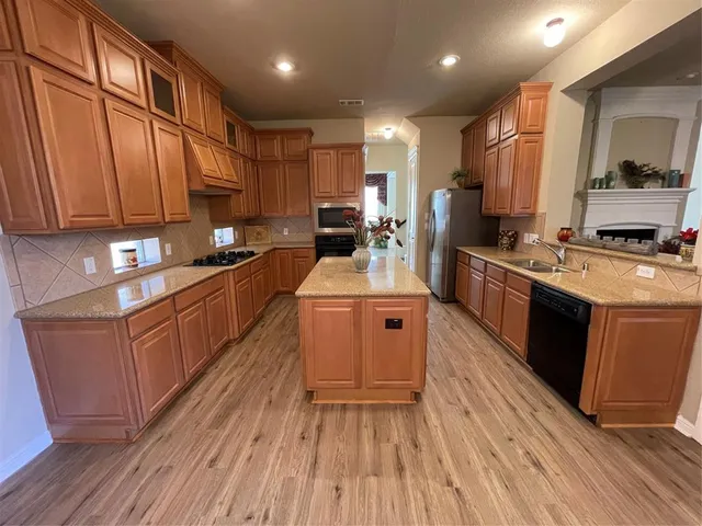 a kitchen with a sink wooden floor and stainless steel appliances