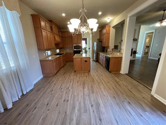 a kitchen with stainless steel appliances a refrigerator oven a sink dishwasher and wooden floor