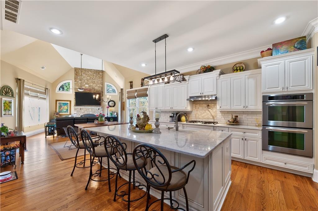 110 Roxbury Row Alpharetta, GA 30004 - Photo 9 of 45 a kitchen with stainless steel appliances granite countertop a stove top oven a sink dishwasher and white cabinets with wooden floor