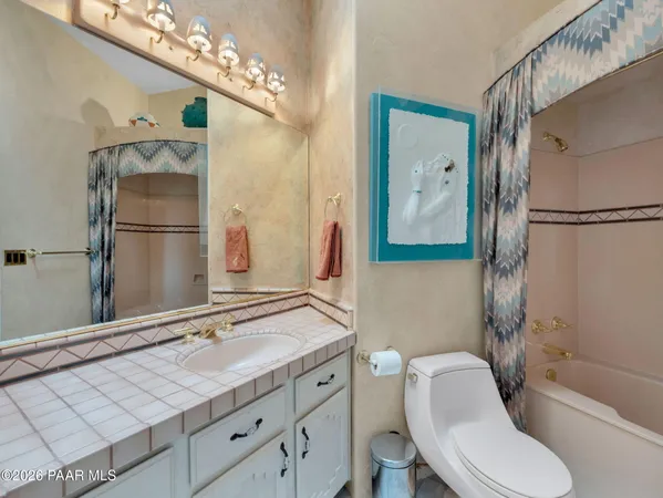 a bathroom with a granite countertop sink a toilet a mirror and shower