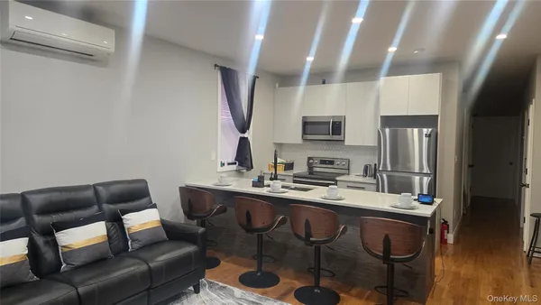 a living room with stainless steel appliances kitchen island granite countertop furniture a rug and a window