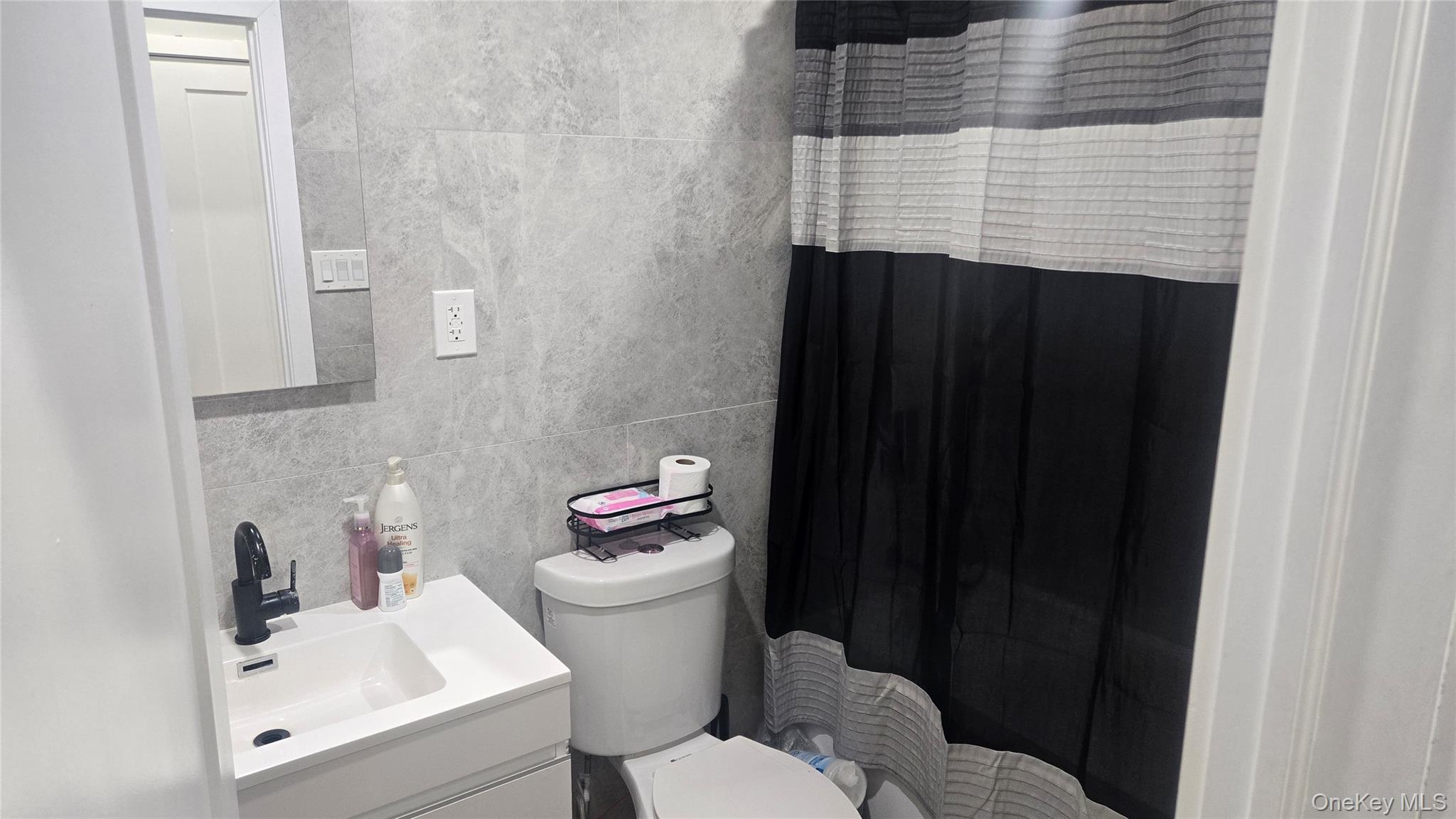 1008 Lenox Road Brooklyn, NY 11212 - Photo 5 of 13 Full bath with tile walls, a shower with curtain, vanity, and backsplash