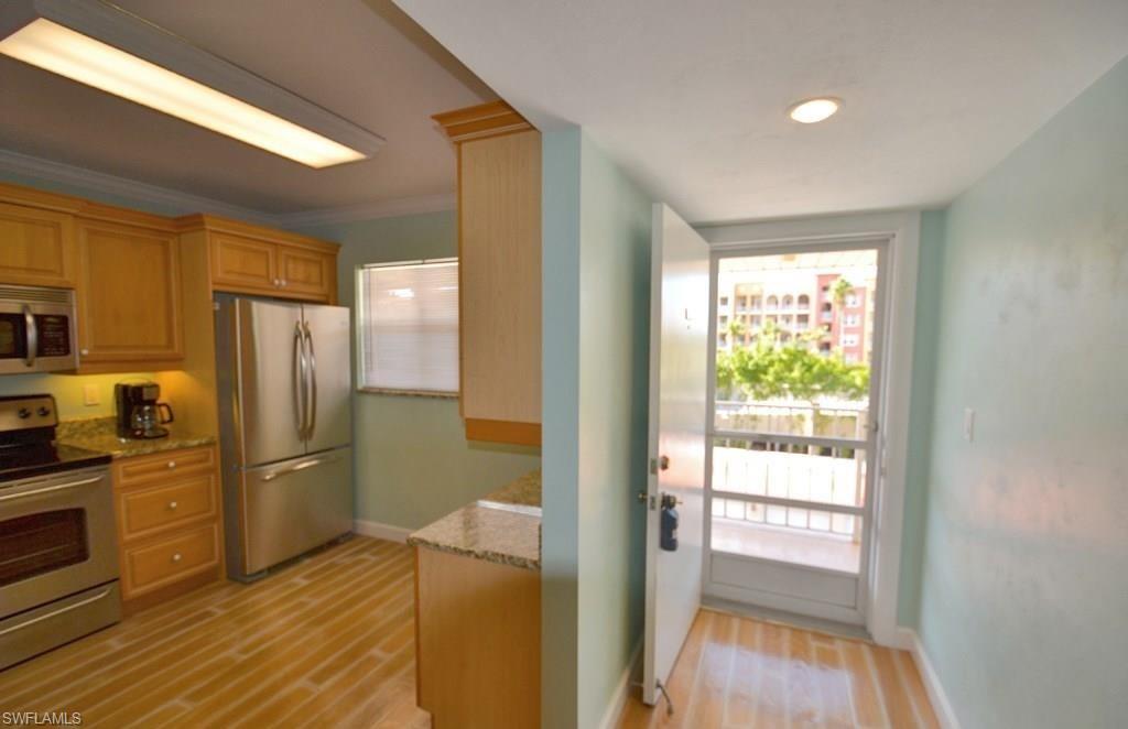 307 Goodlette-Frank Road, Unit 506B Naples, FL 34102 - Photo 11 of 25 a kitchen with a refrigerator and wooden floor