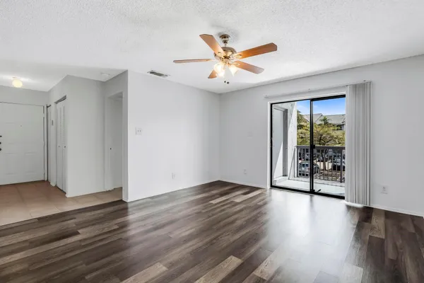 an empty room with wooden floor a ceiling fan and windows