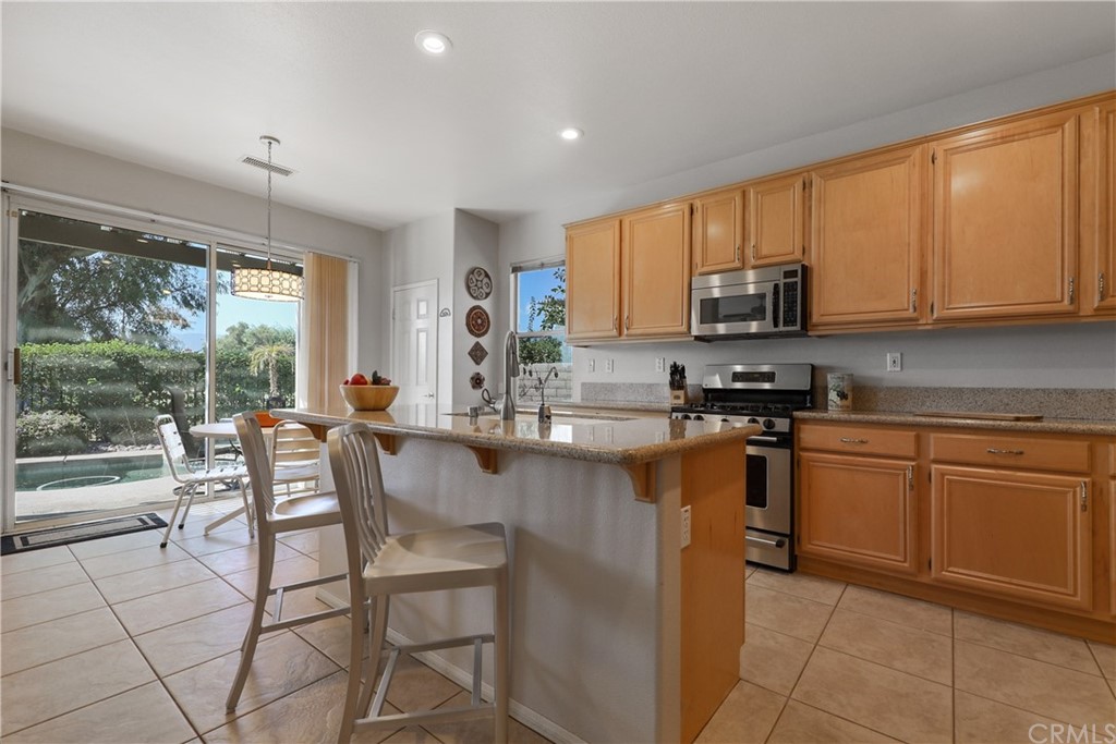 82551 Grant Drive Indio, CA 92201 - Photo 10 of 45 a kitchen with stainless steel appliances granite countertop a stove top oven a sink a dining table and chairs