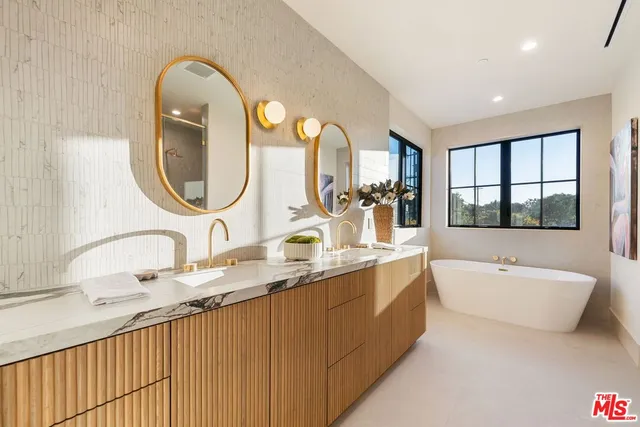 a bathroom with a granite countertop tub a double vanity sink and a large mirror