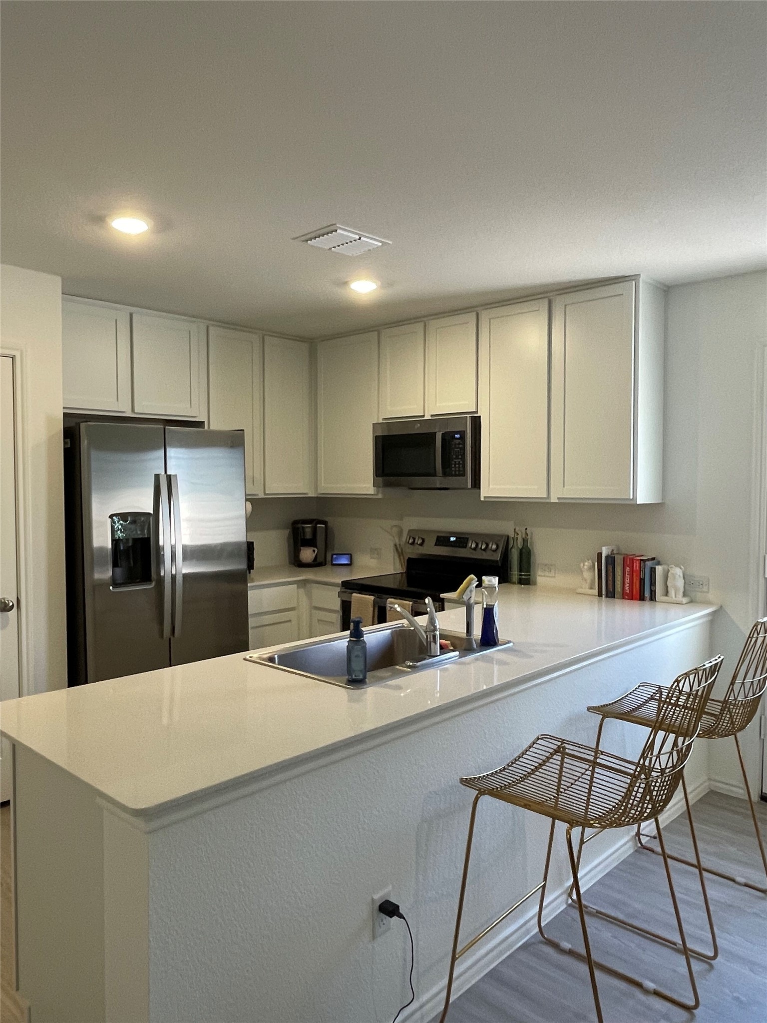 212 Marty Allen Loop Jarrell, TX 76537 - Photo 7 of 13 Modern kitchen featuring white shaker cabinetry and a large peninsula with a stainless steel undermount sink