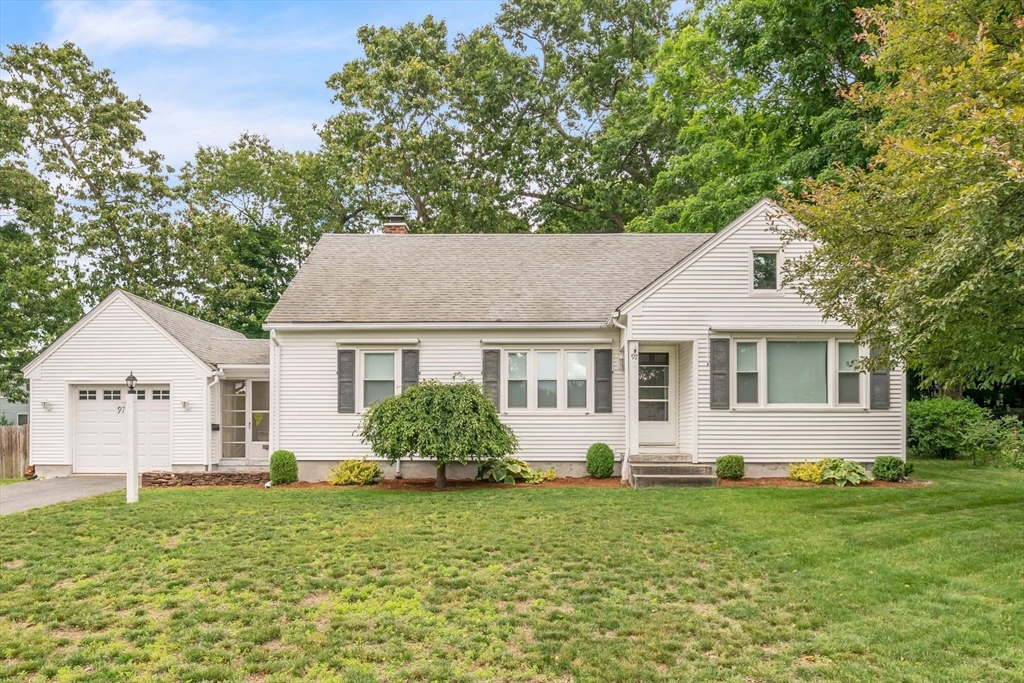 a front view of house with yard and trees in the background