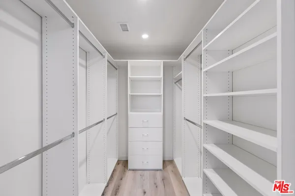 a view of walk in closet with empty racks