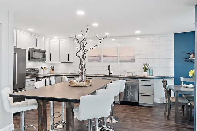 a kitchen with granite countertop white cabinets and stainless steel appliances