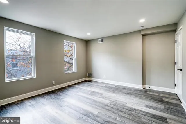 an empty room with wooden floor and windows