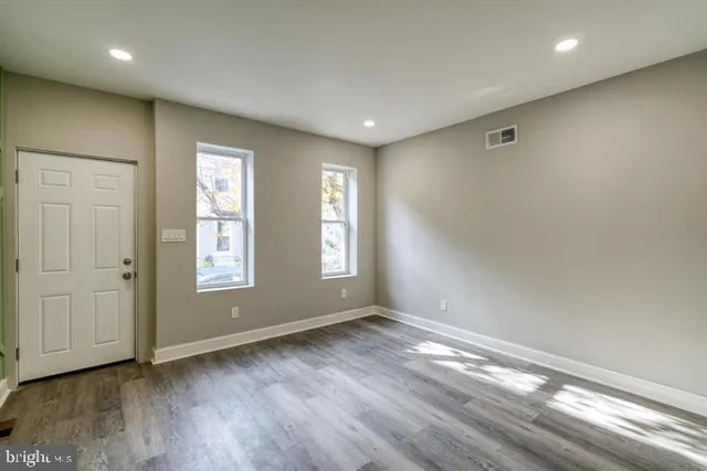 a view of empty room with wooden floor and fan