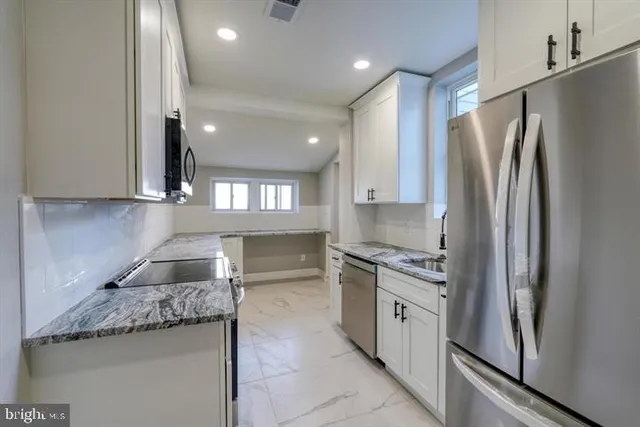 a kitchen with stainless steel appliances granite countertop a refrigerator a stove and a sink