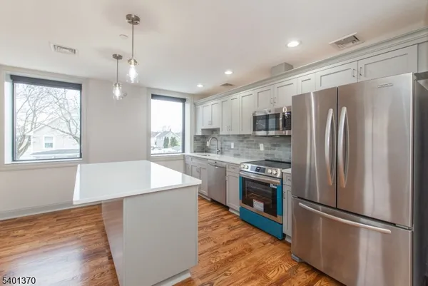 a kitchen with stainless steel appliances granite countertop a refrigerator a stove a sink and a refrigerator with wooden floor