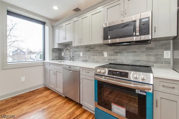 a kitchen with granite countertop a stove top oven cabinetry a sink and dishwasher with wooden floor
