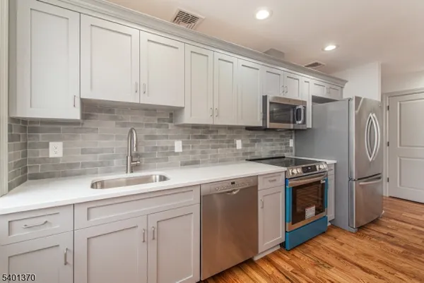 a kitchen with stainless steel appliances granite countertop a sink a stove a refrigerator and cabinets